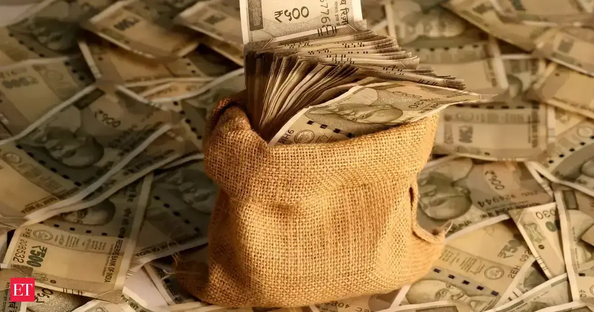 Burlap pouch overflowing with Indian rupee notes and coins scattered on a surface