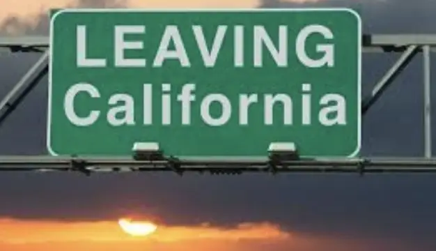 Green highway sign reading "LEAVING California" with blank spaces below, mounted above a road at sunset