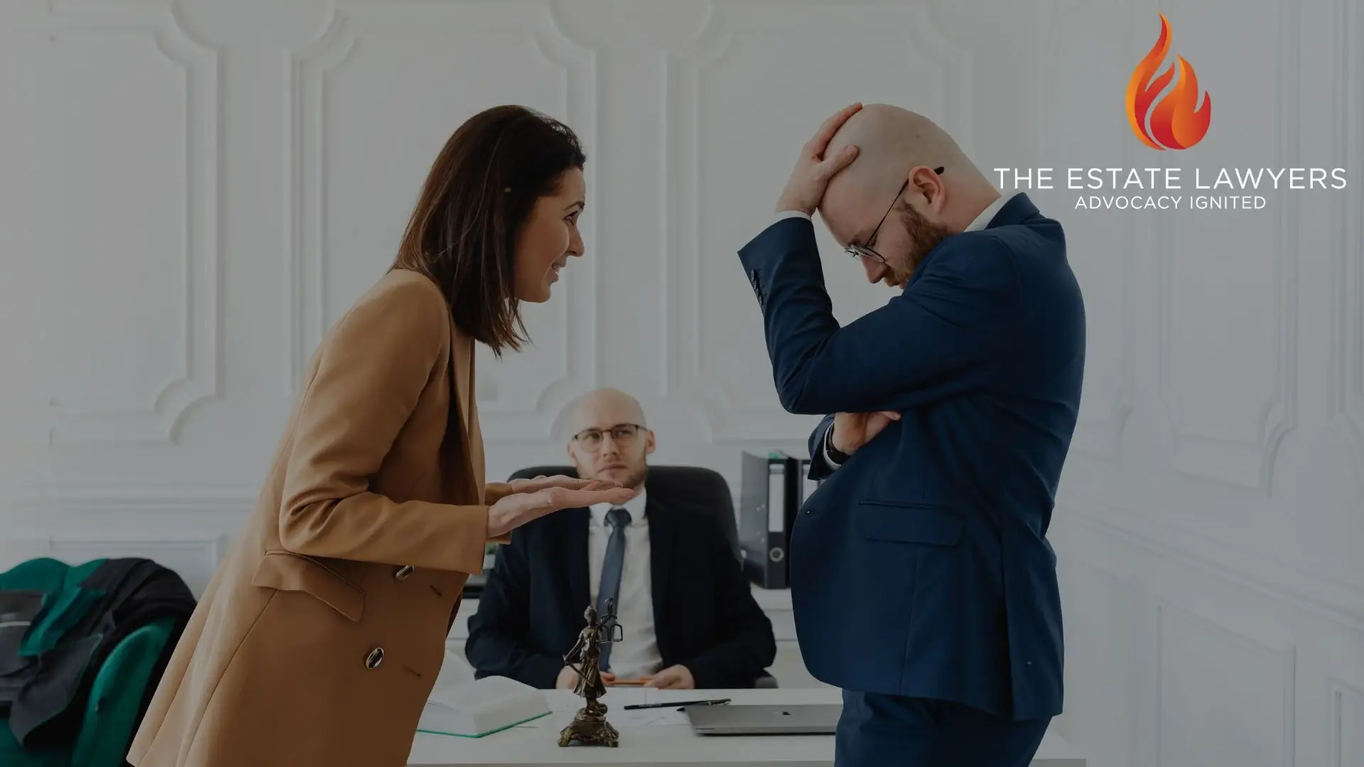 Three professionals in business attire having a discussion in an office setting near a desk with a legal scale