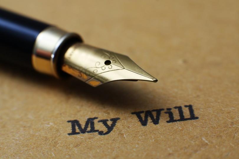Fountain pen with metal nib positioned over text reading "My will" on tan paper