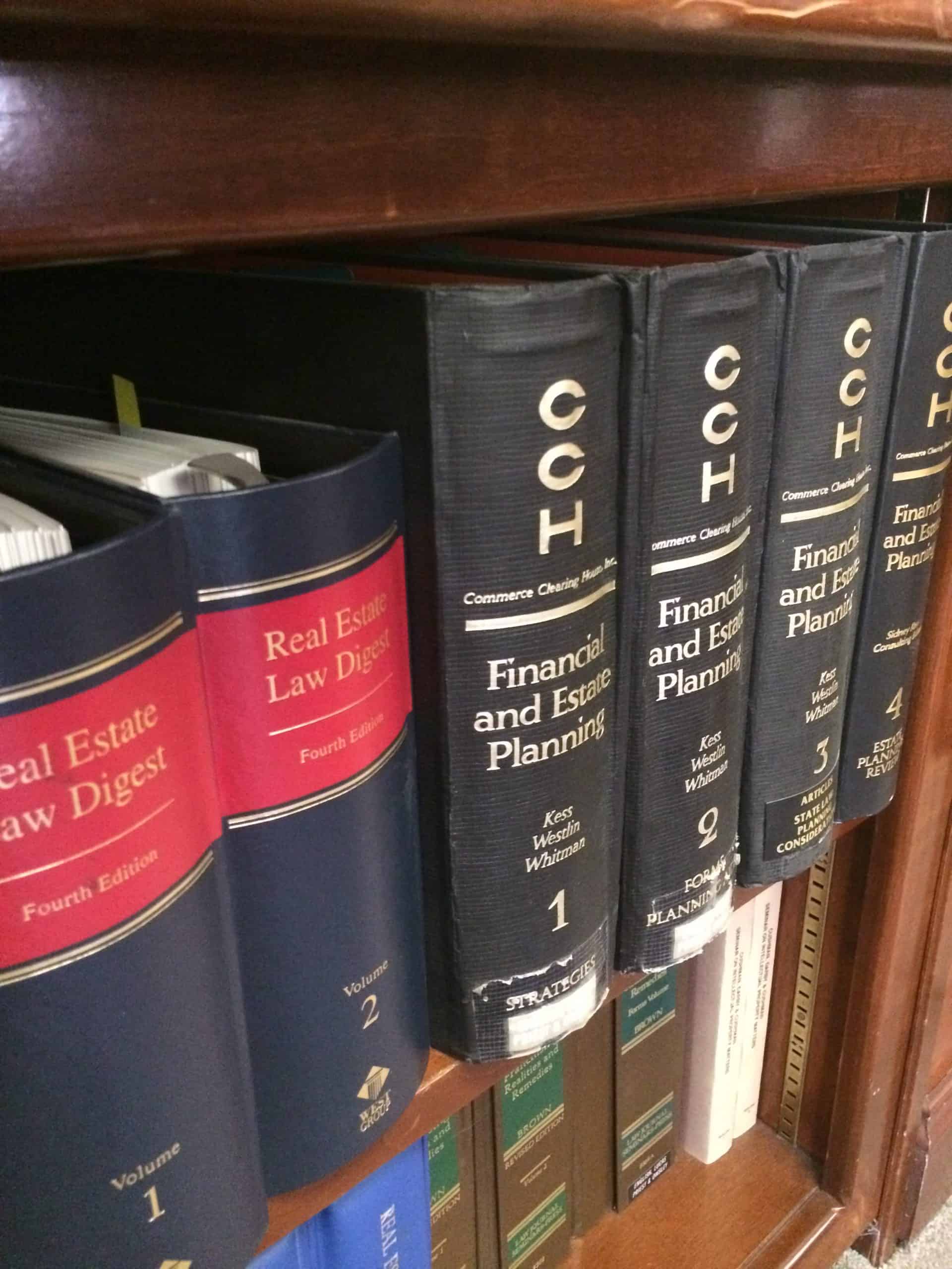 Law books on wooden shelf including Real Estate Law Digest and Financial and Estate Planning volumes